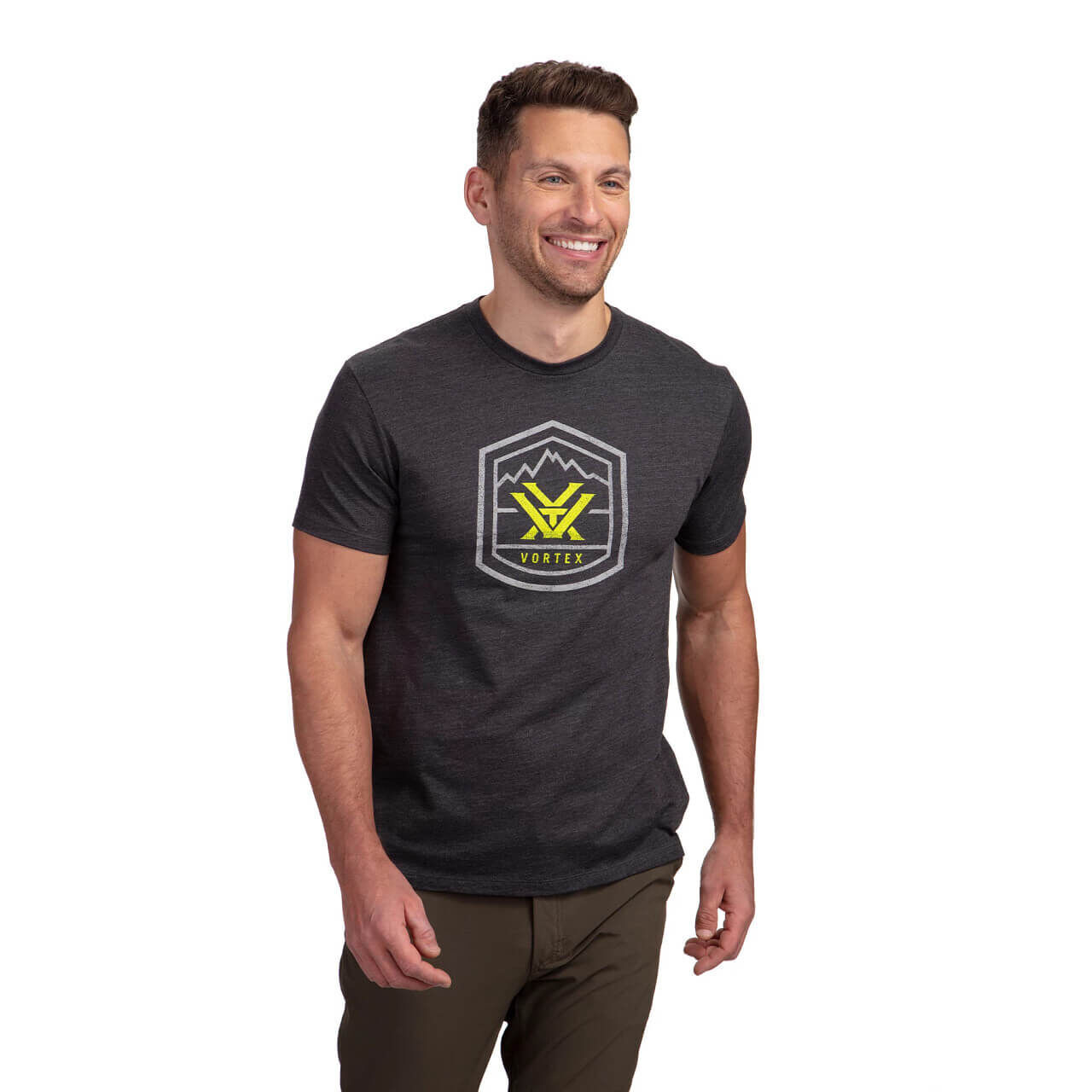 Lächelnder Mann trägt ein dunkelgraues T-Shirt mit gelbem Vortex-Logo und olivgrüner Hose