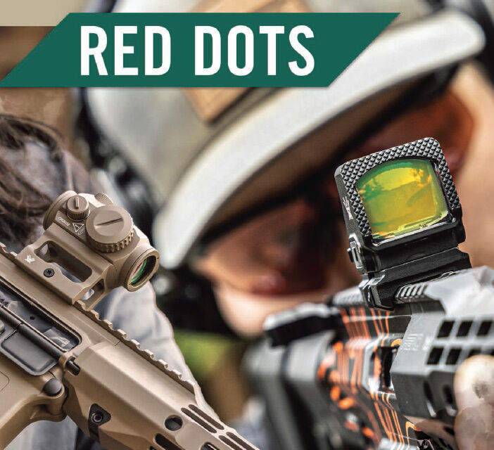Nahaufnahme einer Red Dot Zieloptik, die auf einem Gewehr montiert ist, mit Person im Hintergrund