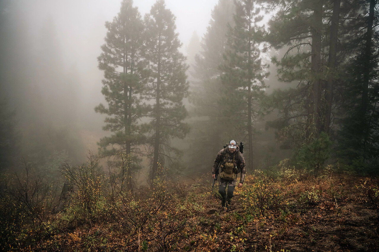 Jäger mit Tarnkleidung und Ausrüstung geht im nebligen Wald