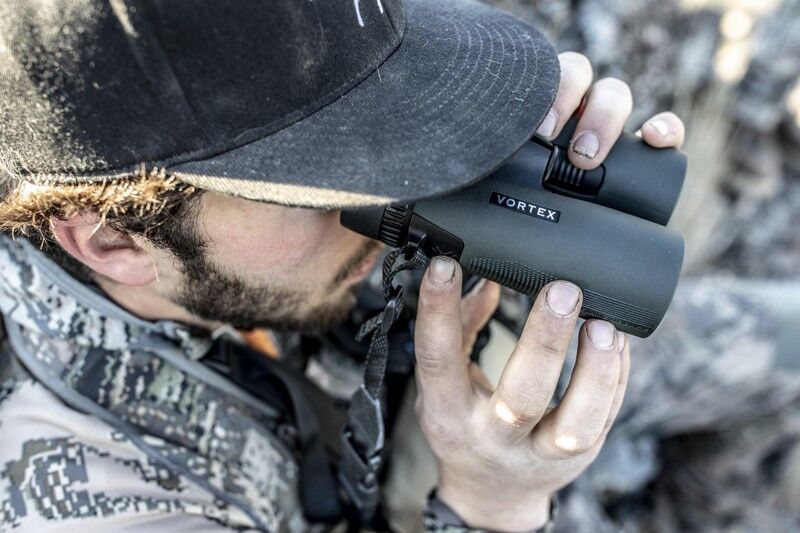 Mann nutzt Fernglas bei der Outdoor-Erkundung Eine Person mit Mütze verwendet ein Vortex-Fernglas im Freien zur Erkundung und Beobachtung.
